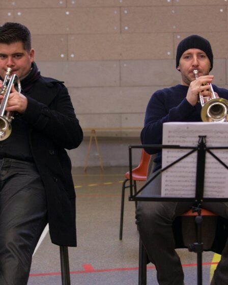 Deux trompettistes en formation, assis avec partitions