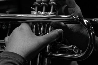 Mains sur les pistons d’une trompette en noir et blanc