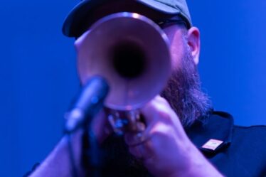 Trompettiste jouant sous un éclairage bleu, protection auditive en concert