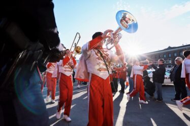 Fanfare de cuivres défilant en costumes traditionnels dans la rue lors d'un festival populaire