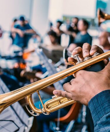 Trompettiste en gros plan tenant son instrument, pupitre de partitions et musiciens d'orchestre en arrière-plan