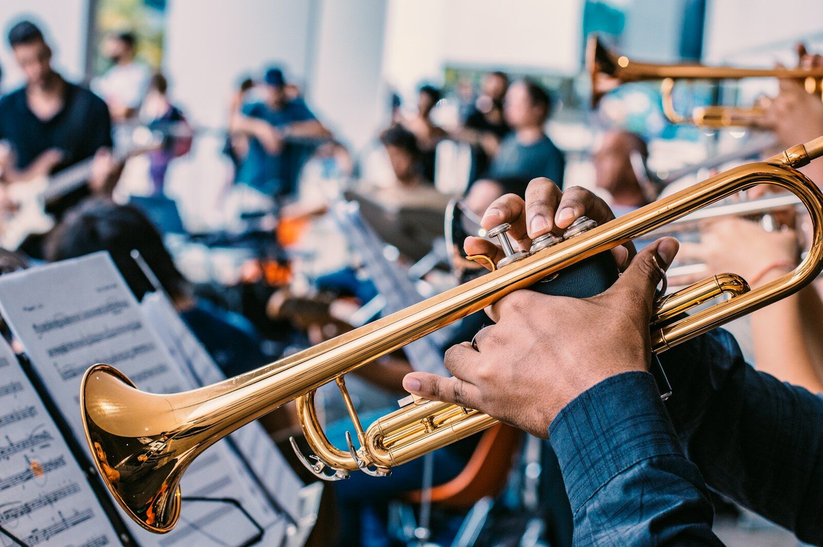 Trompettiste en gros plan tenant son instrument, pupitre de partitions et musiciens d'orchestre en arrière-plan